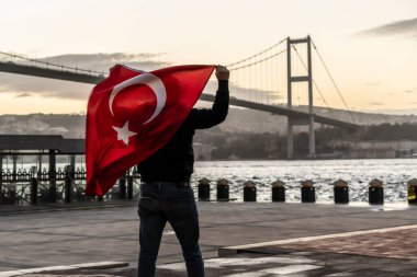 Türk Bayrağı, 15 Temmuz Şehitler Köprüsü (Türkçe: 15 Temmuz Sehitler Koprusu) veya İstanbul 'daki Boğaz Köprüsü' nün önünde bir siluet duruyor. Vatanseverlik kavramı.