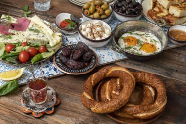 Delicious rich Traditional Turkish breakfast include tomatoes, cucumbers, cheese, butter, eggs, honey, bread, bagels, olives and tea cups. Ramadan Suhoor aka Sahur (morning meal before fasting).  clipart