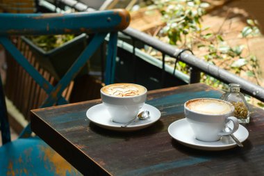 Kafedeki mavi renkli ahşap masada iki beyaz fincan kahve..