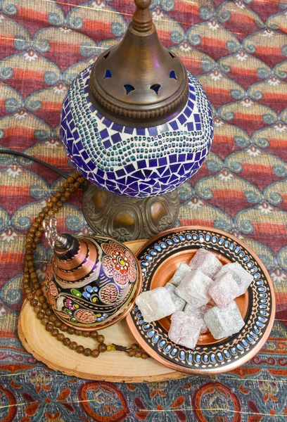 Traditional Turkish delight (blasting cartridge) in traditional hand made cooper bowl with prayer-beads on wood. Fabric background.