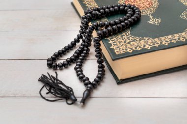 Ahşap zemininde tespih bulunan Kutsal İslam Kitabı Kuran 'ı. Arapça Kur 'an ile. Anlamı: Ramazan Mübarek. Ramazan Kareem. 