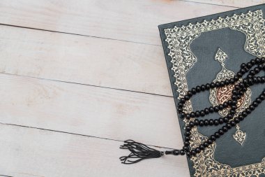 Ahşap zemininde tespih bulunan Kutsal İslam Kitabı Kuran 'ı. Arapça Kur 'an ile. Anlamı: Ramazan Mübarek. Ramazan Kareem. 