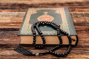 Ahşap zemininde tespih bulunan Kutsal İslam Kitabı Kuran 'ı. Arapça Kur 'an ile. Anlamı: Ramazan Mübarek. Ramazan Kareem. 
