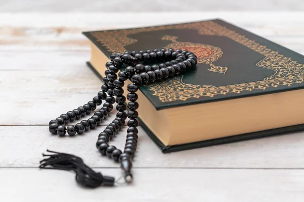 Holy Islamic Book Koran with rosary beads on wooden background. Quran with written arabic calligraphy meaning of Al Quran. Ramadan Mubarak. Ramadan kareem.