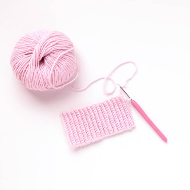 Ball of pink knitting yarn and knitting crochet on white background. Flat lay, top view. Handmade concept.