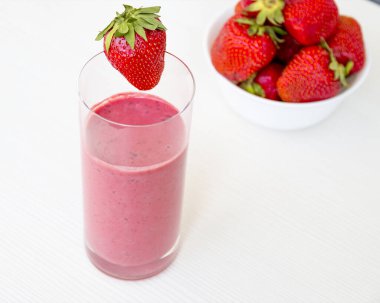 Fresh healthy strawberry smoothie on white wooden background