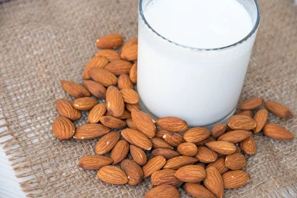 Almond Milk with Almond Nuts on White Wooden Table. White Card with Burlap Strap. A place for Text.