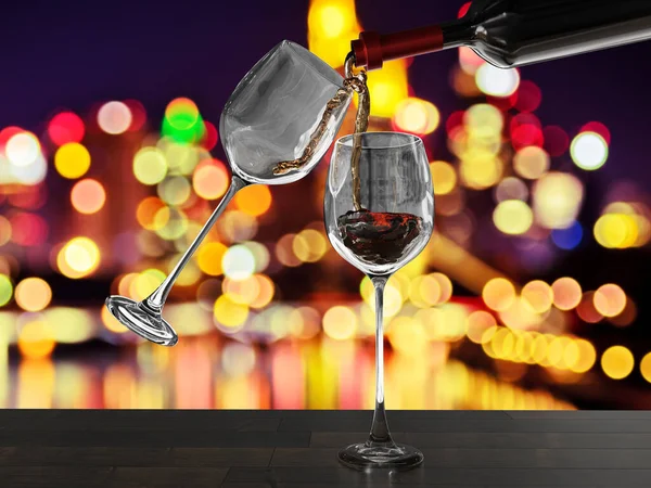 Kırmızı şarap bokeh arkaplanlı iki bardağa döküldü.