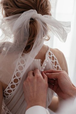 Erkeğin elleri zarif bir elbisenin düğmelerini bağlar.