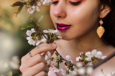 İlkbaharda çiçek açan elma ağaçlarının dallarında kızıl saçlı güzel bir kadın portresi