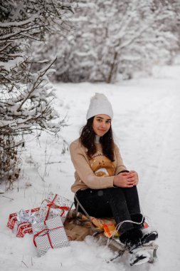 Kızaklı güzel bir kız, Noel ağacı ve kışın karlı bir ormanda hediyeler.