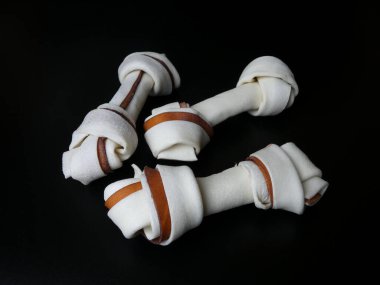 Siyah arka planda üç çiğ köpek çiğniyor.