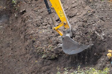 Close-up of an excavator bucket filled with soil during work.