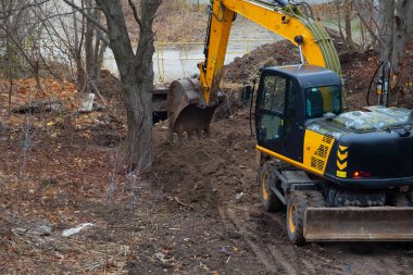 Earthworks with an excavator on a site surrounded by a forest.