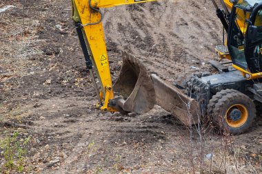 Close-up of excavator-loader buckets on a land construction site, beginning of site development, first stage of construction, clearing the construction site using an excavator.