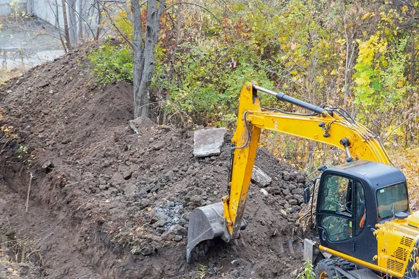 The excavator is digging a pit on a land plot.