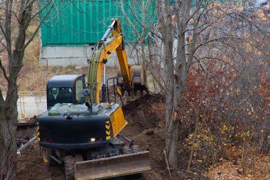 Kazıcının kovası doğanın ortasında bir inşaat sahasında toprağa gömülür..