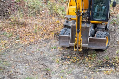 Sonbahar manzarasında kovası olan çalışan bir inşaat kazıcısı..