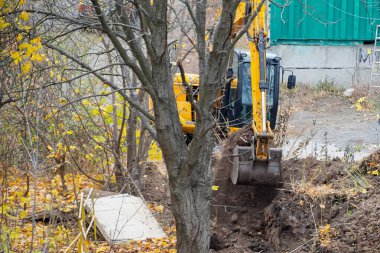 Kazı kovası, gelecekte inşa edilecek bir inşaat sahasında toprağa gömülür..