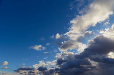 Kümülüs gri-beyaz bulutlar mavi gökyüzüne karşı dalgalı bir desen oluşturur..