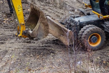 Excavator-loader buckets in close-up on a construction site, the excavator is preparing to work, beginning of construction activities.