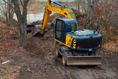The yellow excavator performs tasks at a construction site, scooping soil with its bucket.