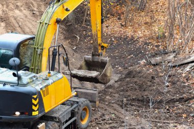 Bir kepçe kazıcı kovası sonbaharda bir inşaat sahasının beton levhasını kaldırıyor, inşaatta temizlik için kazıcı operasyonu, kazıcılar için çeşitli görevler.