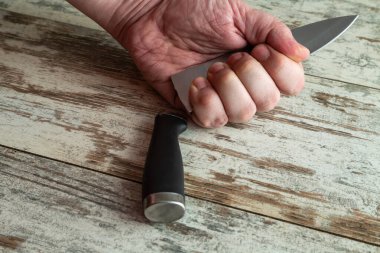 Kalpazanlık ve düşük kaliteli mutfak gereçleri sorunu bir çerçevede: kırık bir bıçağı masanın üstünde tutan bir el. Bu çekim, mutfakta güvenilmez aletler kullanmanın riskini ve tehlikesini vurgular..