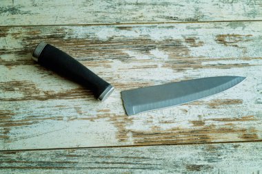 Kırık bir mutfak bıçağı, ahşap bir masanın üzerine uzanır. Mutfak aletlerinin kırılganlığını ve sürekliliğini yansıtır..