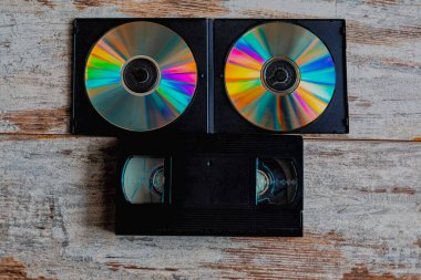 VHS kaset ve CD 'ler ahşap bir yüzey üzerinde bir araya gelerek veri depolama yöntemlerinin geçişini ve dijital teknolojilere geçişini gösteriyor.. 