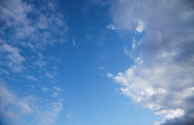 Pofuduk beyaz bulutlu mavi bir gökyüzünün panoramik görüntüsü dinginlik ve aydınlık bir atmosfer yaratıyor. Özgürlüğü, hayalleri ve huzuru simgeliyor..
