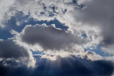 Parlak güneş ışığı yoğun karanlık bulutların arasından kırılarak çarpıcı bir ışık ve gölge oyunu yaratır. Umut ve ilhamı simgeler..