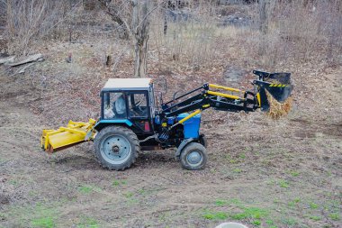 Bir yükleyici, kırılan dalları ve odun parçalarını kaldırıyor. Çevre dostu bir yaklaşım sergiliyor..