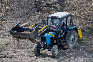 İş zamanı: bir inşaat yükleyicisi atığı temizliyor ve taşıyor. Parkın ve meydanın peyzaj işleri..