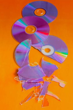 Turuncu arka planda bütün ve kırık CD 'ler, yakın çekim, eski teknoloji, kayıp ve restorasyon arşivi..