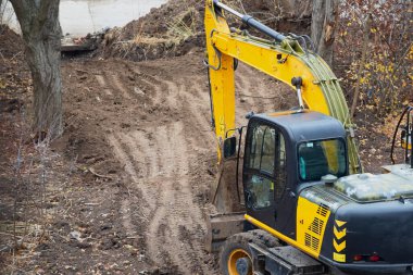 İnşaat alanının önünde katlanmış kovayla kazıcı, inşaatın ilk aşaması, toprak çalışmalarının ilk aşaması..