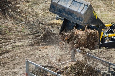 Yükleyici, inşaat için hazırlanan alanın arka planına karşı kamyonete atık boşaltıyor..