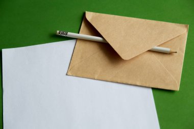 Kaba kağıt üzerinde beyaz bir kalem ve bir zarf. El yazısıyla yazılmış fikirler ve taslaklarla bir dernek..