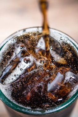 Kola, buzla dolu bir bardağa döküldü.