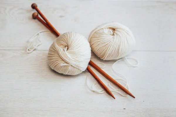 White wool balls and needles on wooden floor Stock Picture