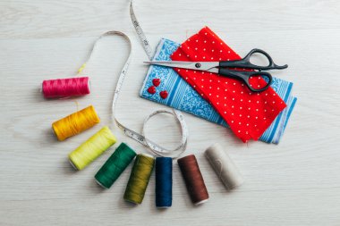 Makas ve renkli makaralar ile kırmızı kumaş