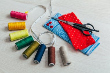 Makas ve metre bandı ile renkli makaralar ile kırmızı kumaş