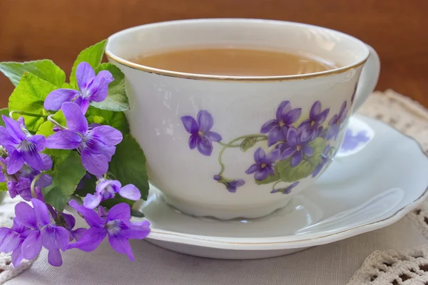 Vintage čaj šálek s motivem fialek s fialovými květy — Stock fotografie
