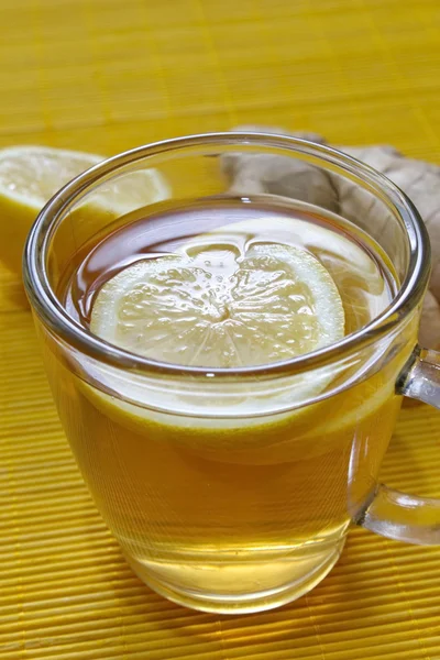 Bicchiere di tè al limone con pezzi di limone e zenzero sul tavolo — Foto Stock