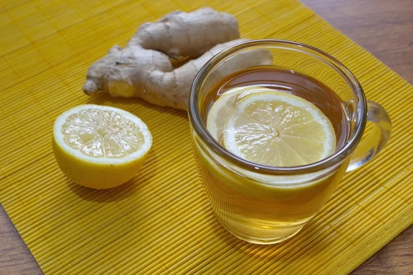 Glass of lemon tea with lemon pieces and ginger on the table — Stock Photo, Image