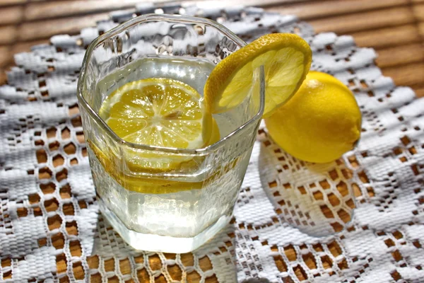 Bicchiere d'acqua con pezzi di limone sul tavolo — Foto Stock