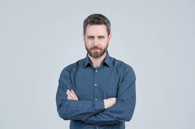 Her erkeğin sahip olması gereken tişört. Sakallı adam kollarını gri arka planda tutuyor. Sıradan bir tarz. Moda erkek giyim. Erkek kıyafetleri. Moda gardırop. Şık kıyafetler. Güven kavramı.