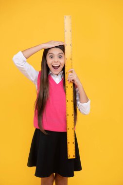Vay canına. Çocuk matematik okuyor. Kök disiplinler. Eğitim konsepti. Boyutunu ölçün. Çocuk boyunda. Ölçüm. şaşırmış genç kız cetvel tutuyor. Okula dönüyorum. Cebir ve geometri.