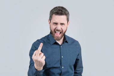 Kızgın adam yüksek sesle bağırıyor. Orta parmak, tek el hareketi, gri arka plan, suç..