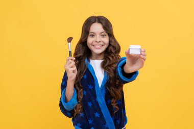 Rahat bornozlu mutlu kız pudra fırçasıyla tımar ediyor, ürünleri sunuyor..